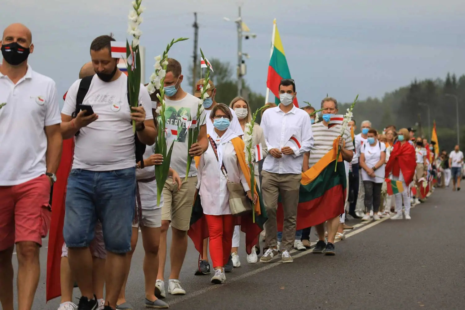 People forming a human chain carrying Lithuanian flags and the white-red-white flag used by the Berusian opposition.